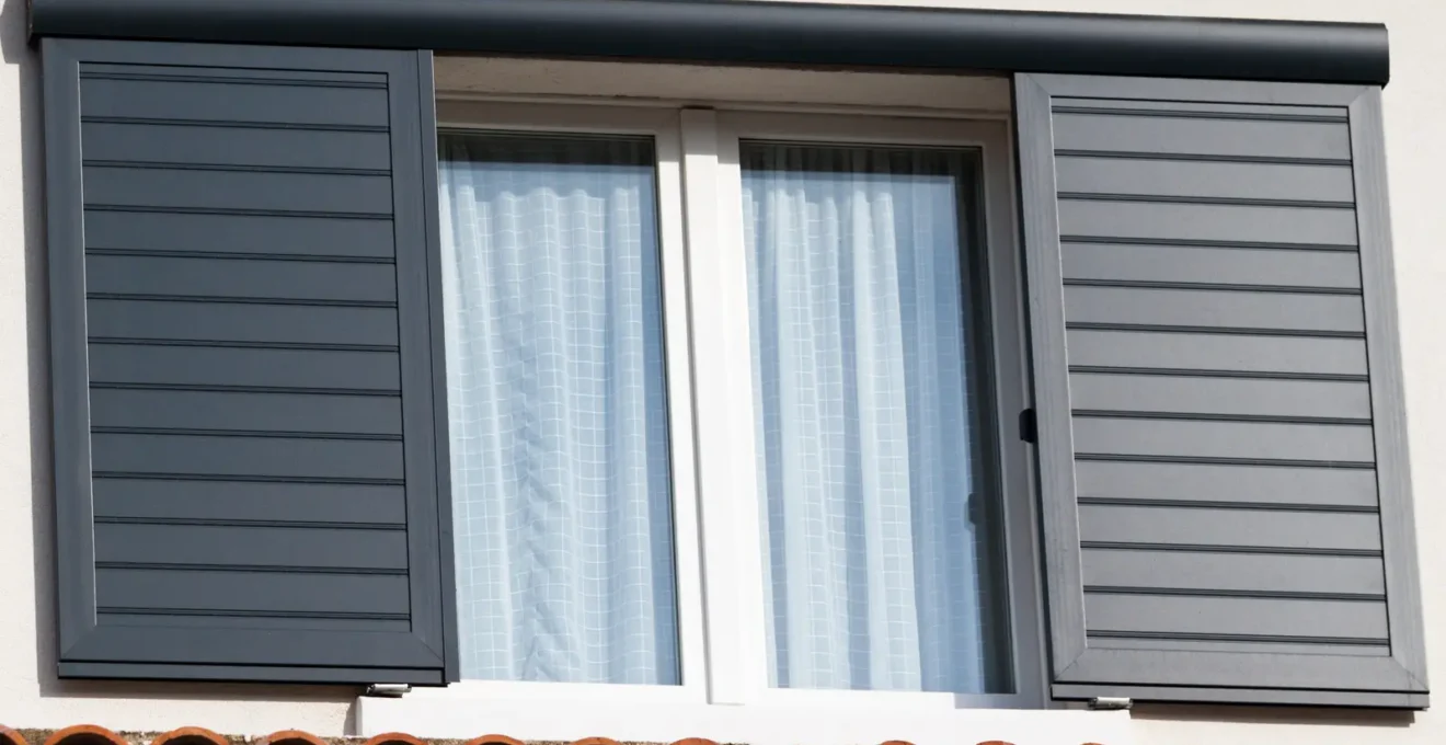 Une personne vérifie les gonds d'un volet battant en aluminium ouvert.