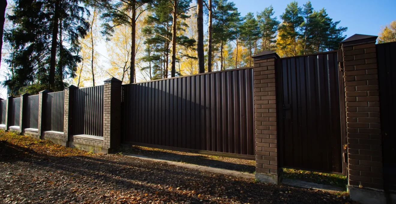 Un particulier nettoie sa clôture en aluminium avec une éponge dans son jardin.